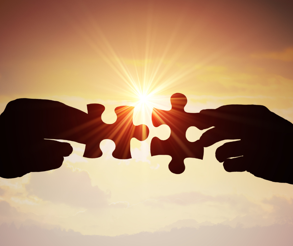 two hands coming together with puzzle pieces in the sun