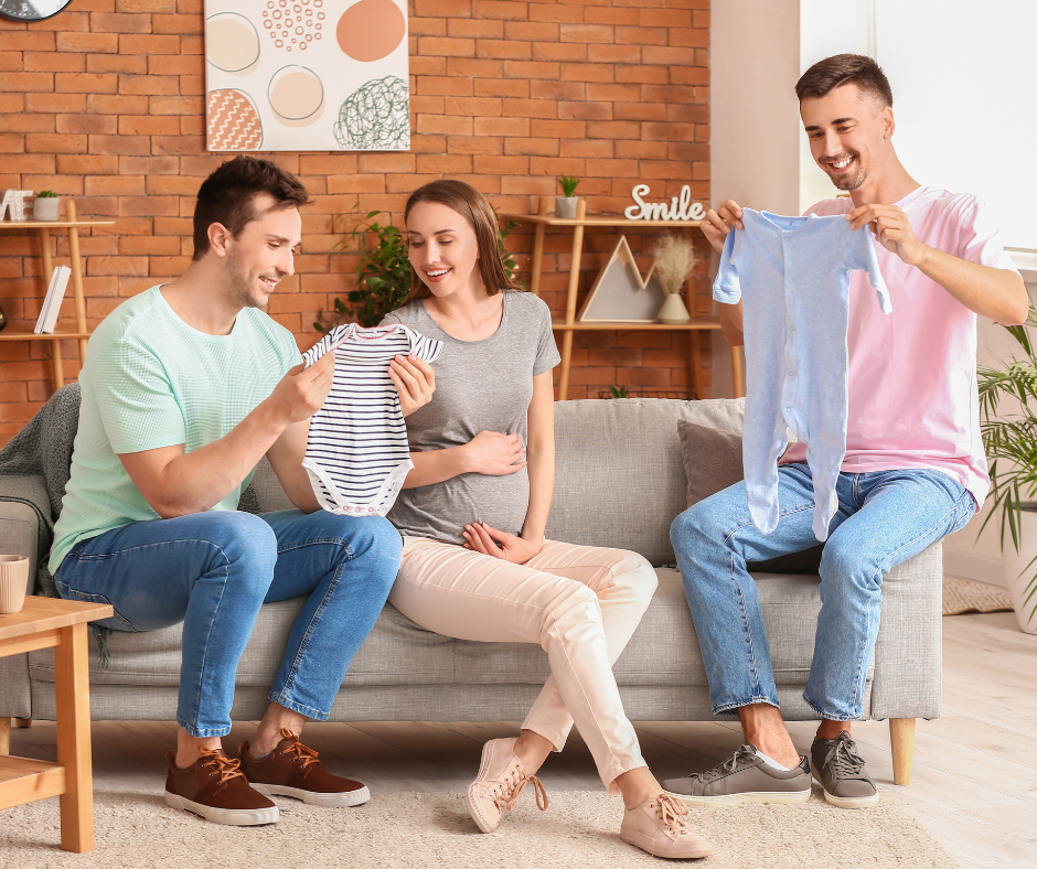 two fathers looking at baby clothes with their surrogate
