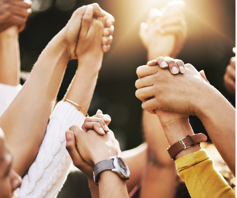 up close shot of a group of people holding hands and raising them in the air